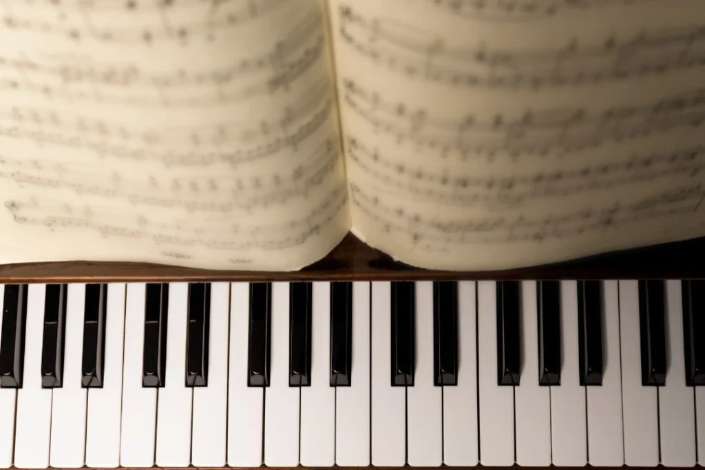 Une partition sur le pupitre d'un piano avec le clavier, les touches noires et blanches.